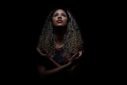 Portraitfotografie Studiofotografie Dramatische Porträtaufnahme einer Frau mit lockigem Haar vor schwarzem Hintergrund