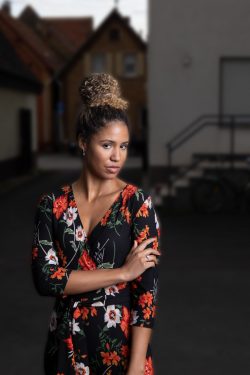 Portraitfotografie Studiofotografie Frau in Blumenmusterkleid steht vor einem Gebäude