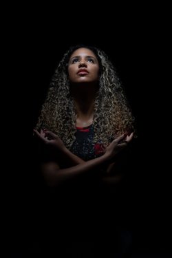 Portraitfotografie Studiofotografie Frau mit lockigem Haar in dramatischem Licht vor schwarzem Hintergrund