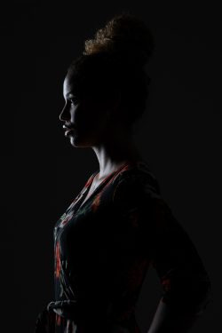 Portraitfotografie Studiofotografie Silhouette einer Frau mit lockigen Haaren vor schwarzem Hintergrund