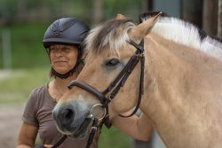 Reitstunde Fotografie Aloys Peter Trenz Frau mit Fahrradhelm neben Fjordpferd im Park