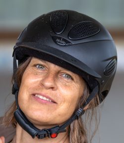 Reitstunde Fotografie Aloys Peter Trenz Nahaufnahme einer Frau mit schwarzem Fahrradhelm und freundlichem Ausdruck
