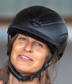 Reitstunde Fotografie Aloys Peter Trenz Frau mit Helm, Nahaufnahme, lächelnd, hellblaue Augen