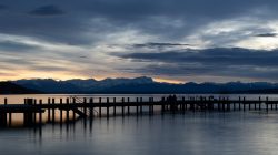 Starnberger See Januar 2023 Fotografie Aloys Peter Trenz Romantische Abenddämmerung über dem ruhigen See mit Blick auf die Berge Starnberger See Januar 2023 Fotografie Aloys Peter Trenz Abenddämmerung am See mit Bergen im Hintergrund und einem langen Steg