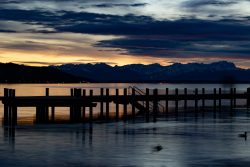 Starnberger See Januar 2023 Fotografie Aloys Peter Trenz Ein Steg erstreckt sich in den ruhigen See, während die Sonne untergeht Starnberger See Januar 2023 Fotografie Aloys Peter Trenz Sonnenuntergang über einem See mit Steg und Bergkulisse