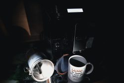 Storytelling Sorge Dich nicht lebe - The Day after Kaffeemaschine mit umgefallenem Kaffeebecher und Tasse auf dunklem Hintergrund