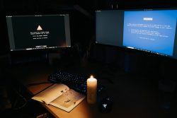 Storytelling Sorge Dich nicht lebe - The Day after Zwei Monitore mit Fehlerbildschirm in dunklem Raum, beleuchtet von einer Kerze