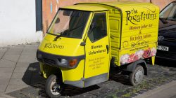 Urban Life und Streetfotografie Frankfurt Juni 2022 Gelbes Dreiradfahrzeug des Rosarium-Blumenlieferservice, geparkt auf einer Straße in Frankfurt