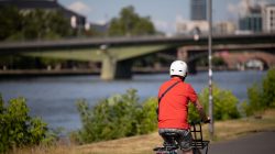 Urban Life und Streetfotografie Frankfurt Juni 2022 Mann mit Helm fährt Fahrrad entlang des Flusses