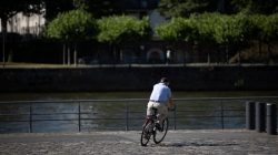 Urban Life und Streetfotografie Frankfurt Juni 2022 Mann fährt Fahrrad entlang eines Flusses auf Kopfsteinpflaster