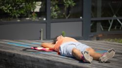 Urban Life und Streetfotografie Frankfurt Juni 2022 Person liegt entspannt auf einem Holzdeck in der Sonne