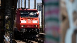 Urban Life und Streetfotografie Frankfurt Juni 2022 Roter DB-Zug fährt über Eisenbahnbrücke bei sonnigem Wetter
