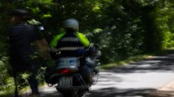Urban Life und Streetfotografie Frankfurt Juni 2022 Motorradfahrer im schnellen Fahrt durch einen grünen Wald auf einer Straße
