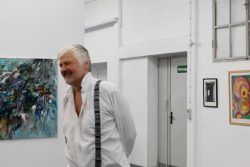 Vernissage Künstlerin Andrea Simon Thema Spuren Kunsthalle Frankfurt Juli 2024 Älterer Mann in weißem Hemd in Kunstgalerie lächelt neben Gemälden