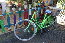 Insel Wangerooge Landschaftsfotografie Mai 2020 Grünes Fahrrad mit Korb vor bunt bemalten Holzmännern in einer urbanen Umgebung