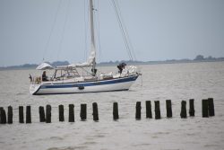 Insel Wangerooge Landschaftsfotografie Mai 2020 Segelboot auf stürmischer Nordsee umgeben von hölzernen Wellenbrechern