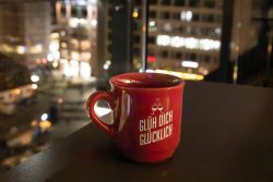Weihnachtliches Frankfurt Dezember 2024 Rote Tasse mit Spruch vor beleuchteter Stadtlandschaft