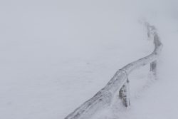 Winterwelt Taunus Landschaftsfotografie Verschneites Gelände mit Frostspuren und Holzgeländer im Nebel