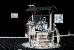 Frühling Bad Vilbel Ostern 2026 Bronzeskulptur eines Brunnen mit Figuren in einer nächtlichen Umgebung