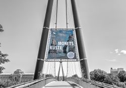 Städel Museum - Monet - Monets Küste Die Entdeckung von Étretat Mai 2026 Das Plakat auf der Brücke kündigt die Ausstellung 'Monets Küste' in Berlin an Städel Museum - Monet - Monets Küste Die Entdeckung von Étretat Mai 2026 Plakat auf Brücke bewirbt Monets Küste Ausstellung in Berlin