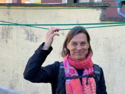 Meissen Mai 2026 Lächelnde Frau mit rosa Schal draußen vor einer gelben Wand