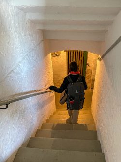 Meissen Mai 2026 Frau mit Rucksack geht eine beleuchtete Treppe in einem weißen Steintunnel herunter