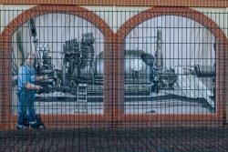 Meissen Mai 2026 Industrie-Wandgemälde mit historischem Maschinenmotiv hinter Zaun