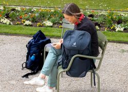 Paris Juni 2026 Frau auf Parkbank mit Deuter-Rucksack in einem blühenden Park