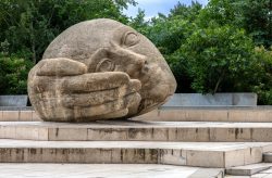 Paris Juni 2026 Große Steinskulptur eines ruhenden Kopfes in einem Park umgeben von Bäumen