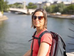 Paris Juni 2026 Frau mit Rucksack an Flussufer bei sonnigem Wetter