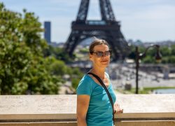 Paris Juni 2026 Frau in blauer Bluse vor Eiffelturm an einem sonnigen Tag