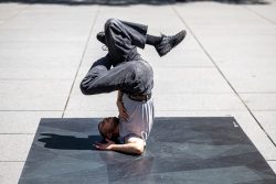Paris Juni 2026 Tänzer in grauem T-Shirt und schwarzer Hose führt Kopfstand im Freien aus