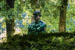 Paris Juni 2026 Bronzestatue im grünen Park vor Drahtzaun und üppigem Laub