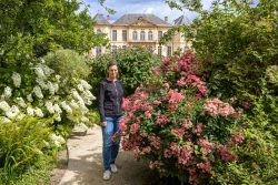 Paris Juni 2026 Person steht in einem blühenden Garten vor einem historischen Gebäude
