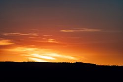 Partielle Sonnenfinsternis am 12.08.2026 Panorama eines farbenfrohen Sonnenuntergangs über einer Silhouette eines Hügels