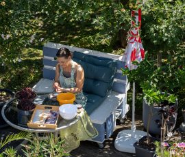 Die Kirschen in Nachbars Garten Frau sitzt in einem gemütlichen Garten, umgeben von Pflanzen und Obstbäumen