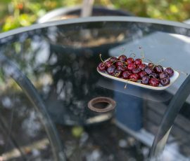 Die Kirschen in Nachbars Garten Frische Kirschen auf einem Glastisch im Garten
