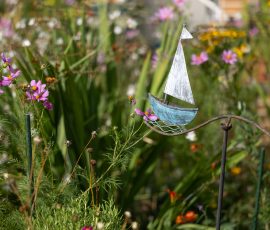 Die Kirschen in Nachbars Garten Garten mit dekorativem Segelboot und blühenden Wildblumen