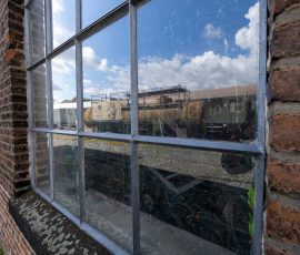 Museumseisenbahn Hanau e. V. Bahnbetriebswerk, Heideäcker 1, 63457 Hanau Fotos von Aloys Peter Trenz Industriegelände mit Eisenbahnwaggons und blauem Himmel im Spiegelbild eines alten Fensters