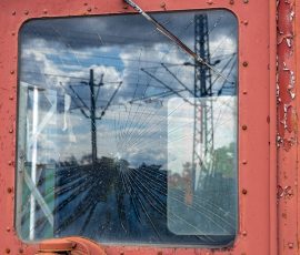 Museumseisenbahn Hanau e. V. Bahnbetriebswerk, Heideäcker 1, 63457 Hanau Fotos von Aloys Peter Trenz Altes Lokomotivfenster mit Spinnennetz-Rissen und Blick auf Strommasten
