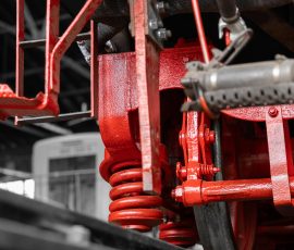 Museumseisenbahn Hanau e. V. Bahnbetriebswerk, Heideäcker 1, 63457 Hanau Fotos von Aloys Peter Trenz Nahaufnahme roter Zugfederung unter einem historischen Eisenbahnwaggon
